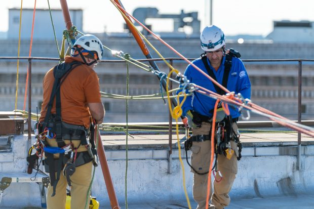 Baltimore, MD - Todd Medeiros and Marc Tiritilli from Over the Edge, a fundraising group specializing in high angle rigging, works on high angle rigging on top of 100 N. Charles Street Friday June 14, 2019.