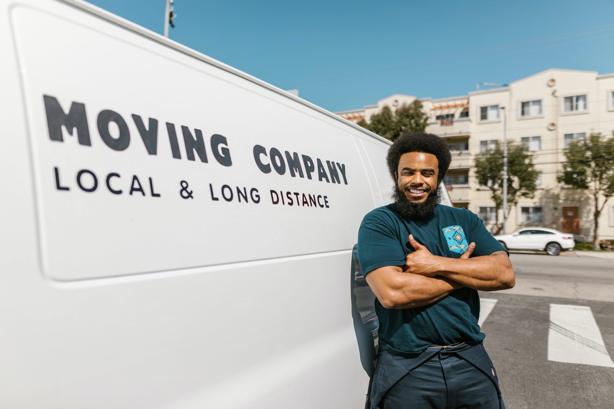 Professional mover standing next to a white van with his arms crossed.