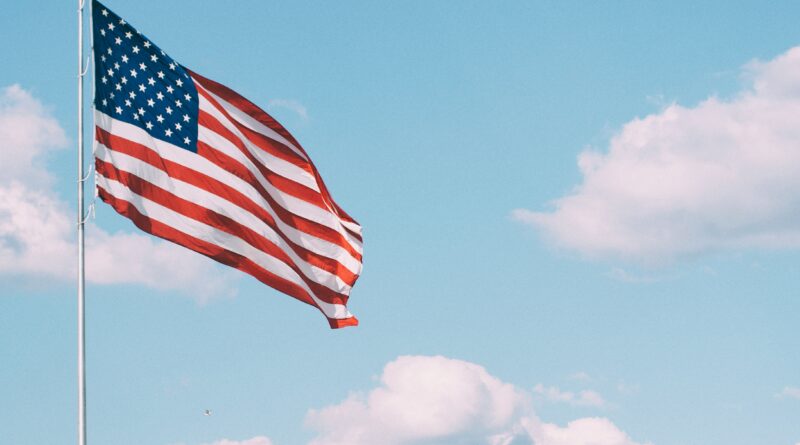 American flag against blue sky with clouds