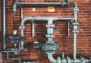 Home plumbing pipes against a brick wall