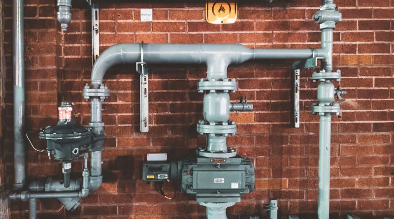 Home plumbing pipes against a brick wall
