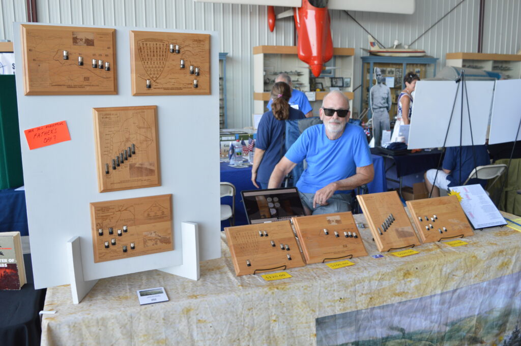 D-Day plaque by Day of Days Productions. Sand Historian Joel Johnson with his plaques displayed at the 2026 MAAM WWII Weekend. (Anthony C. Hayes)