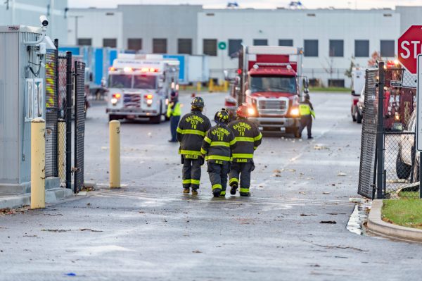 Extensive damage can be seen at the Amazon fulfillment center in Baltimore after sunrise Saturday morning. The damage is a result of a severe weather event late Friday night. Firefighters and special operations teams from Baltimore City Fire Department are seen working to locate and remove a second victim. (Mike Jordan/BPE Photo)