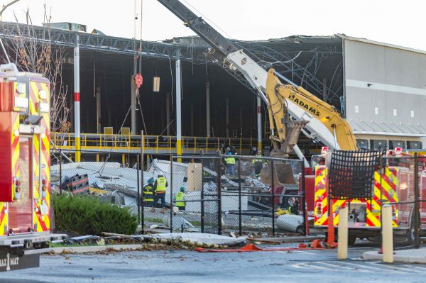 Extensive damage can be seen at the Amazon fulfillment center in Baltimore after sunrise Saturday morning. The damage is a result of a severe weather event late Friday night. Firefighters and special operations teams from Baltimore City Fire Department are seen working to locate and remove a second victim. (Mike Jordan/Photo)