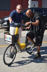 Jim Duffney gives veteran Onzea Robinson a quick demonstration of the Baltimore Bike Share pedelec bike. (Anthony C. Hayes)