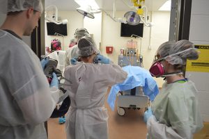 Students from The Community College of Baltimore County crowd around two donated bodies at the University of Maryland School of Medicine, April 5, 2016. They wear protective face gear to protect themselves from formaldehyde that can cause upper respiratory problems. Capital News Service Photo by Leo Traub. 