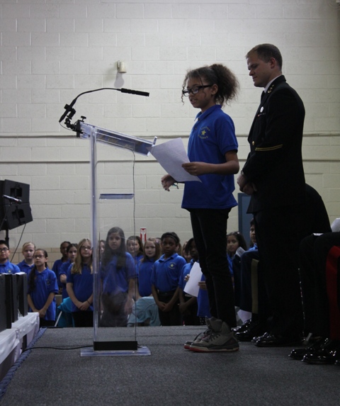 A fifth-grader from Hilltop Elementary School reads a message of gratitude while Naval Academy Midshipman Matt Robbins listens. (Elyzabeth Marcussen) 