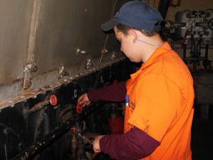 Evan Milbourne adjusts a valve on one of the Brown's two steam boilers. (Anthony C. Hayes)