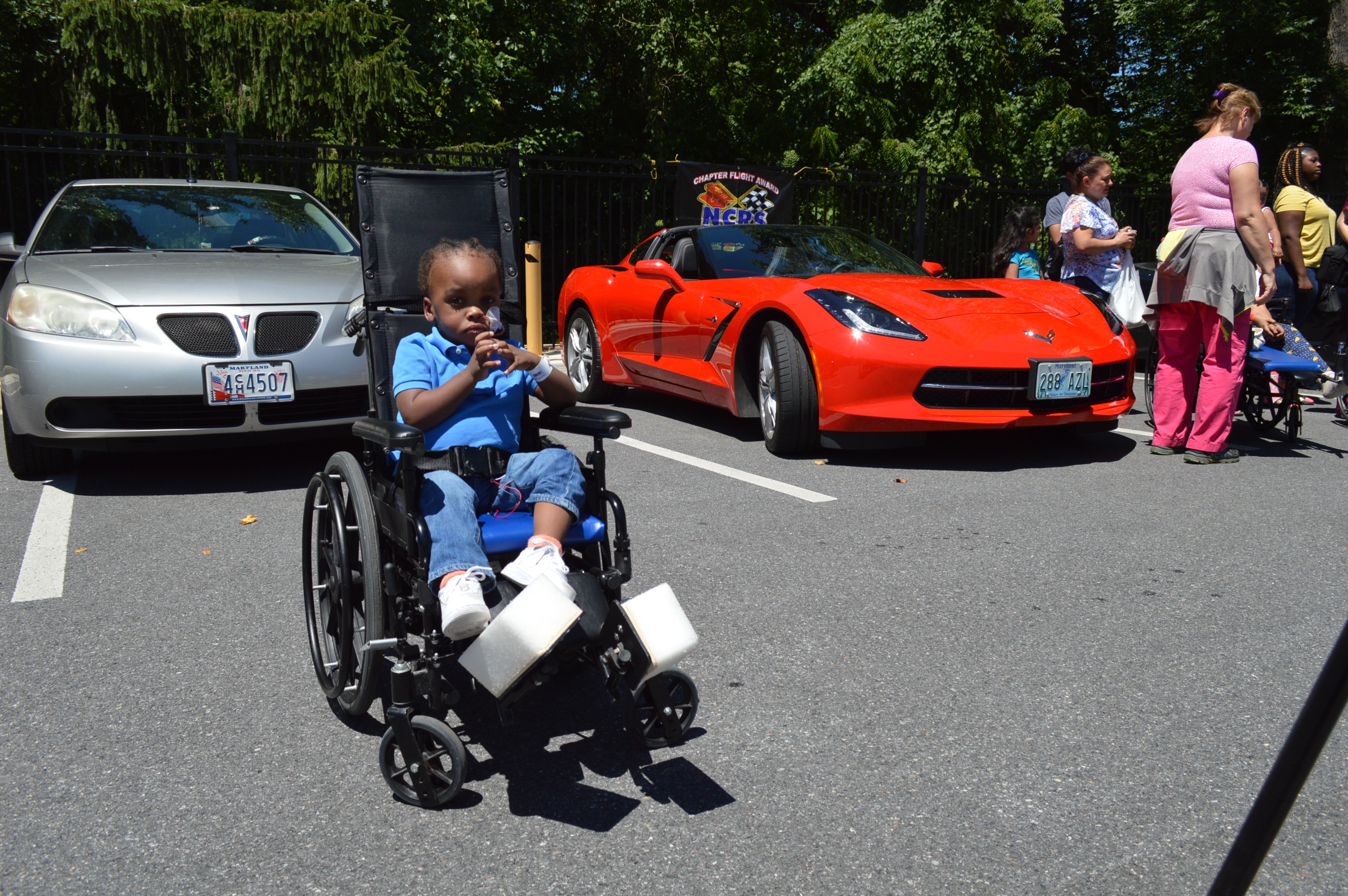 A wheelchair-bound child awaits his turn to sit in a Chevrolet Corvette. On Saturday, July 7, 2018, the Mason-Dixon Chapter of the National Corvette Restorers Society (NCRS) paid its annual visit to the Mt. Washington Pediatric Hospital in Baltimore (credit Anthony C. Hayes).