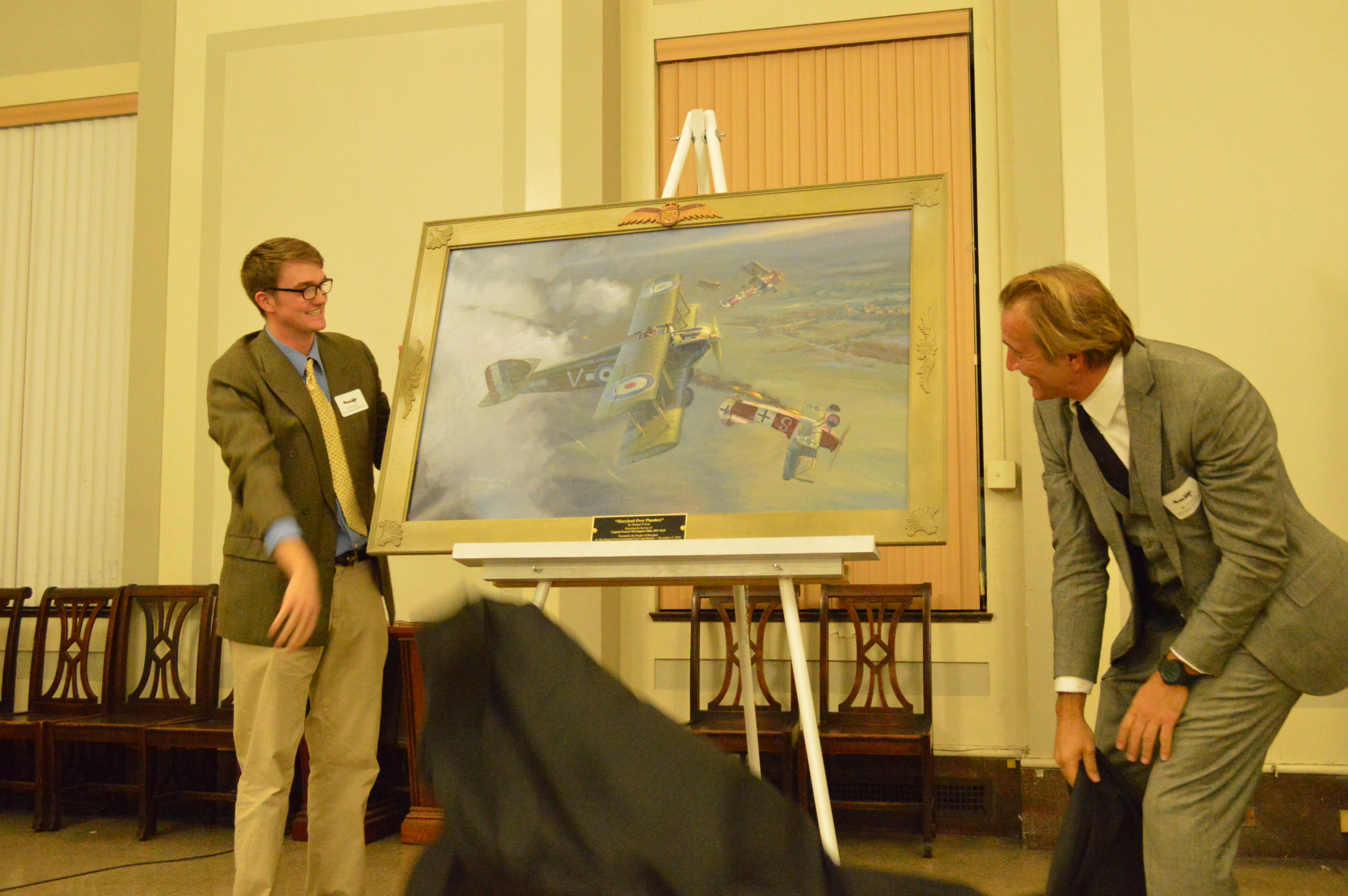 Francis Warrington Gillet IV and his father, Francis Warrington Gillet III, remove the cover from the Michael O’Neal painting titled "Maryland Over Flanders". (Anthony C. Hayes)