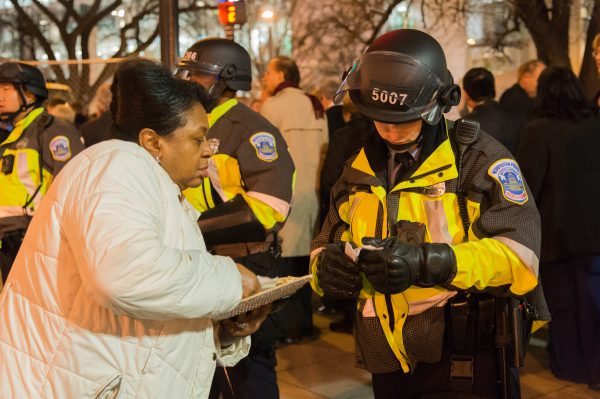 Inauguration Day: A police officer in riot formation and gear assists a party goer with directions. (Michael Jordan)