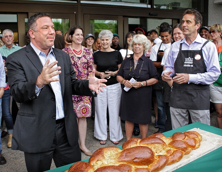 The Whole Food supermarket opened in August 2014 in the former Rouse Co. headquarters on Lake Kittamaqundi. There for a bread-breaking ceremony were, from left, Howard County Executive Ken Ulman, County Council members Courtney Watson and Mary Kay Sigaty; Del. Liz Bobo, the former Howard County executive; and Whole Foods Mid-Atlantic President Scott Allshouse. Ulman had worked hard to get a Whole Foods to Columbia. County government photo by Scott Kramer. Courtesy of Columbia Archives