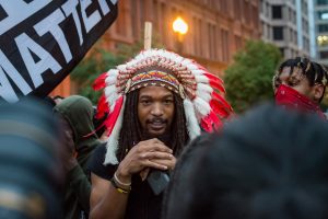 Pierre Branson calls himself an "Indigenous Aboriginal" during a march at New York Ave NW and 15th St. NW (Mike Jordan/BPE)